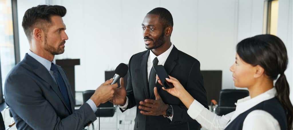 businessman being interviewed by two reporters