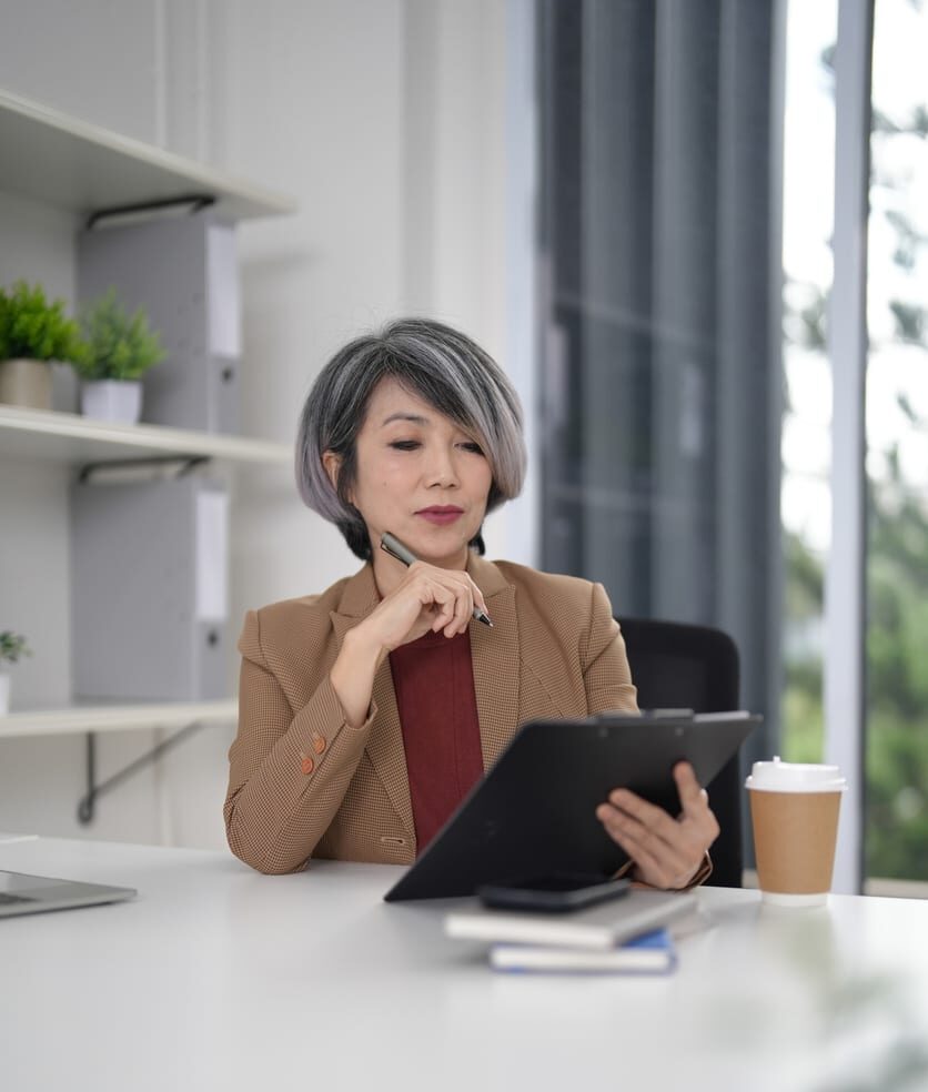 Older adult businesswoman professional looking at a tablet at a desk
