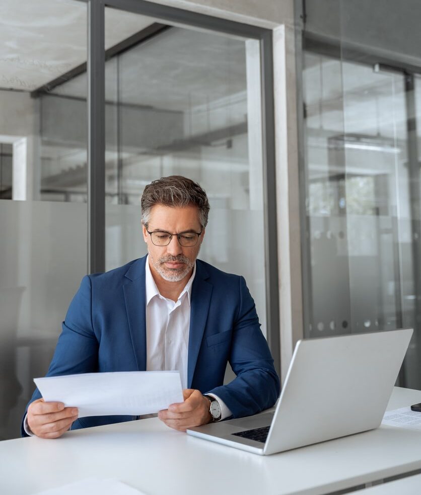 businessman in blue blazer and glasses seated with computer